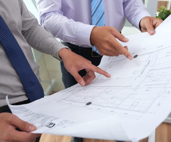 Close-up image of architects discussing blueprint of new building